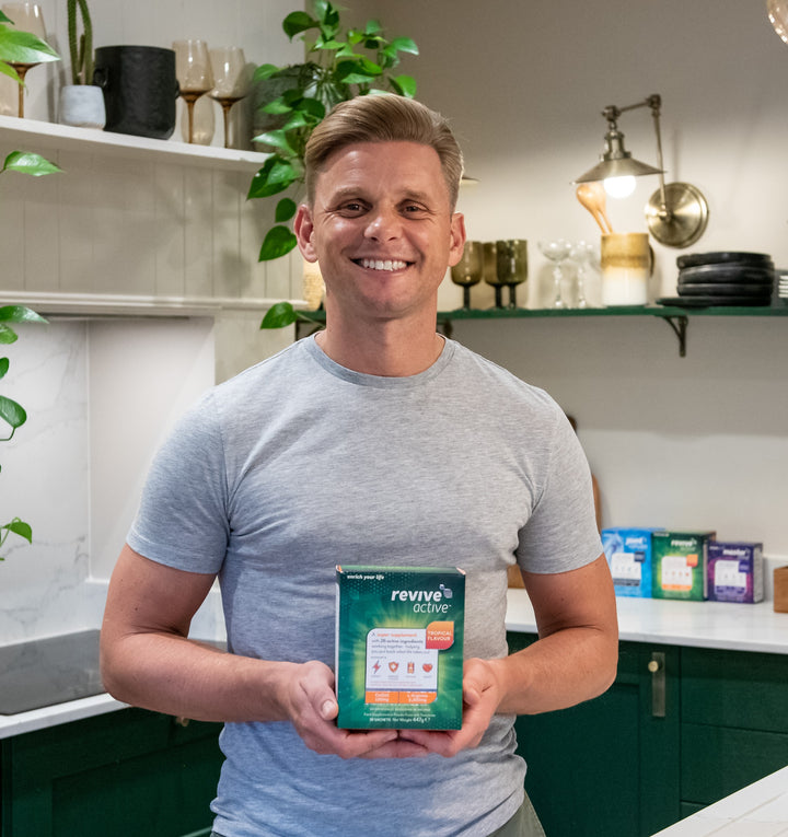 Jeff Brazier holding a Revive Active Supplement Box in his kitchen